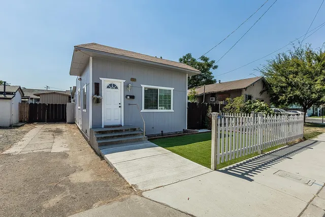 a view of a house with a small yard and a large parking space