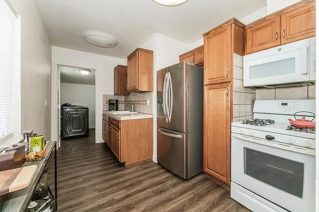 a kitchen with a refrigerator a stove top oven and a wooden floor