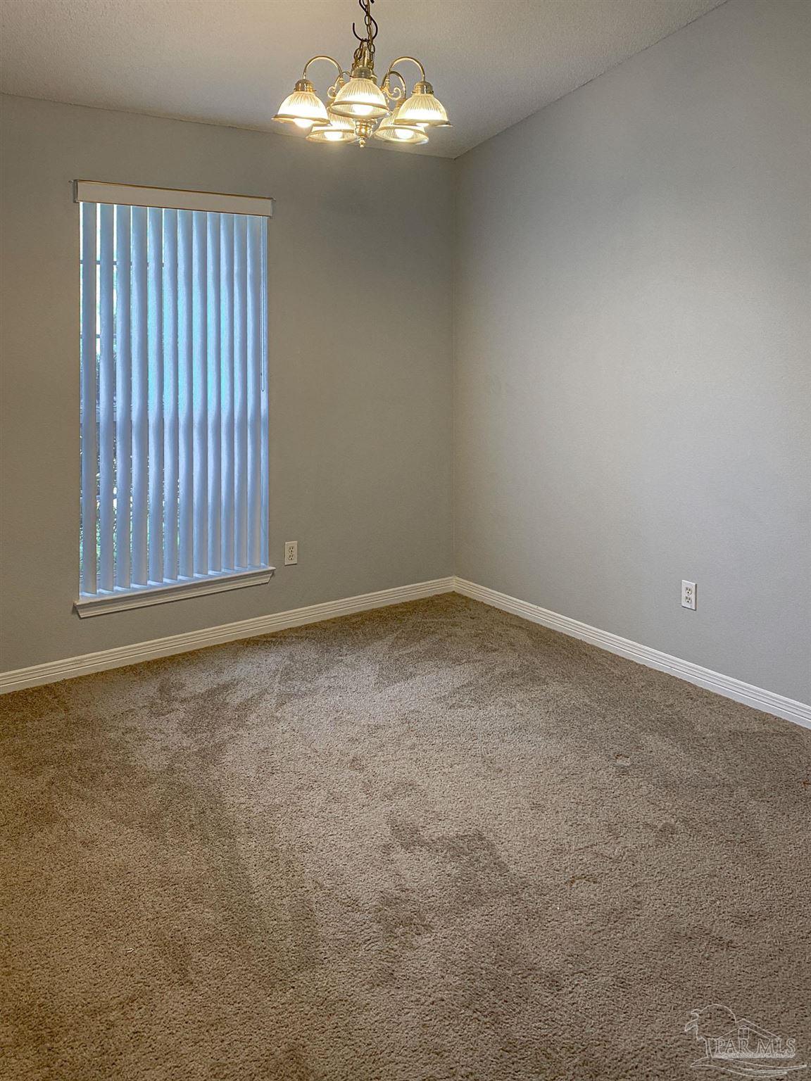 12611 Meadson Road Pensacola, FL 32506 - Photo 19 of 22 an empty room with a chandelier fan and windows
