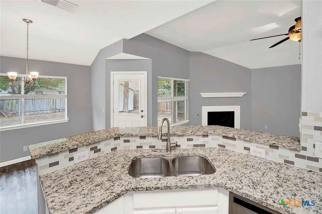 140 Riley Cove Kyle, TX 78640 - Photo 14 of 26 a kitchen with kitchen island granite countertop a sink and a white cabinets
