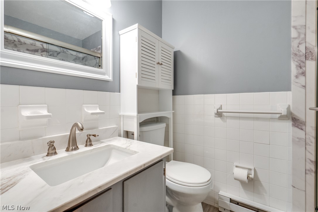 3070 Kent Road Stow, OH 44224 - Photo 35 of 43 Bathroom featuring vanity, a baseboard heating unit, tile walls, and a shower with shower door.