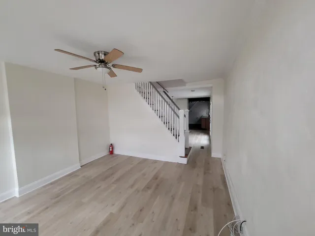 a view of empty room with wooden floor and fan