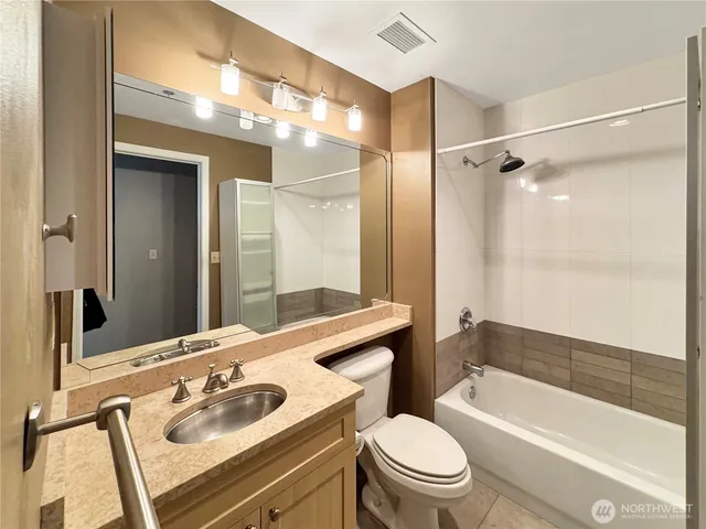 a bathroom with a sink vanity mirror bathtub and toilet