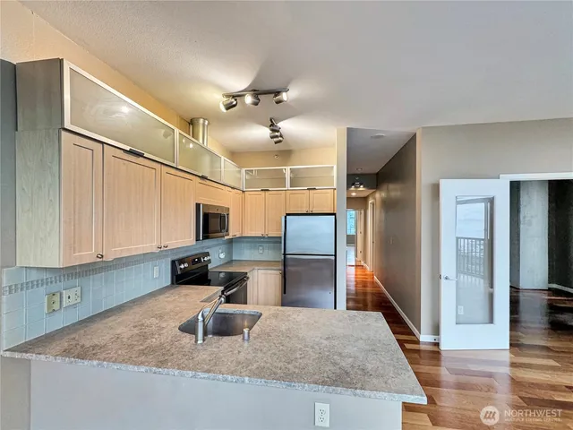 a kitchen with kitchen island a sink stainless steel appliances and a counter top space