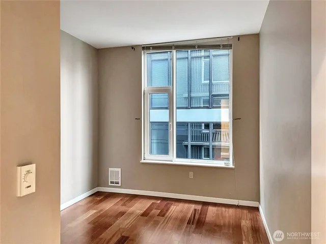 a view of an empty room with wooden floor and a window