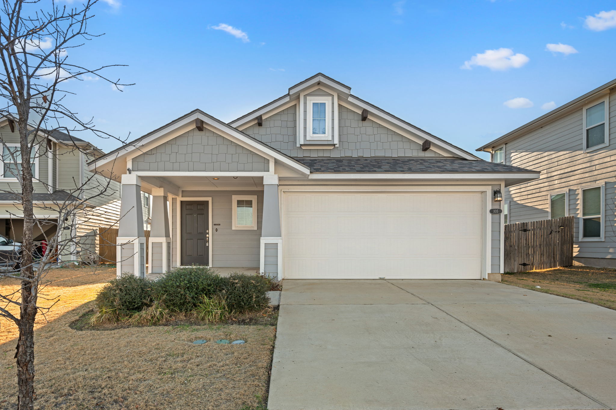 View of front facade featuring driveway, covered porch, roof with shingles, and an attached garage