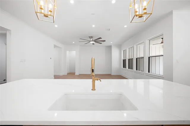 a large white kitchen with a refrigerator a stove a sink and a wooden floors