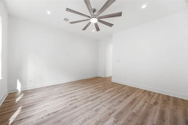 an empty room with a window and a ceiling fan