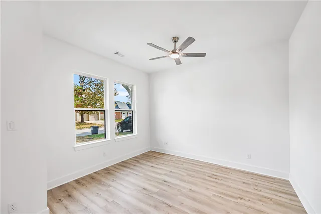 a view of empty room with wooden floor and fan