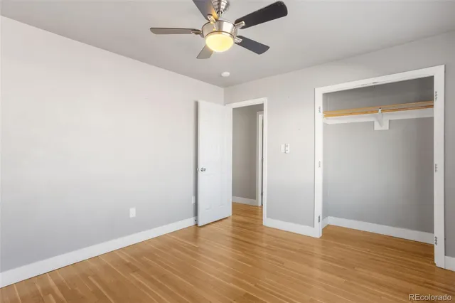 an empty room with wooden floor a ceiling fan and closet