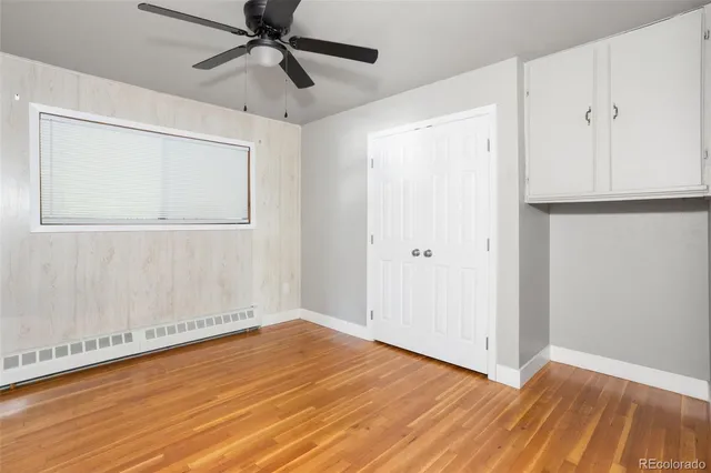 a view of empty room with wooden floor and fan