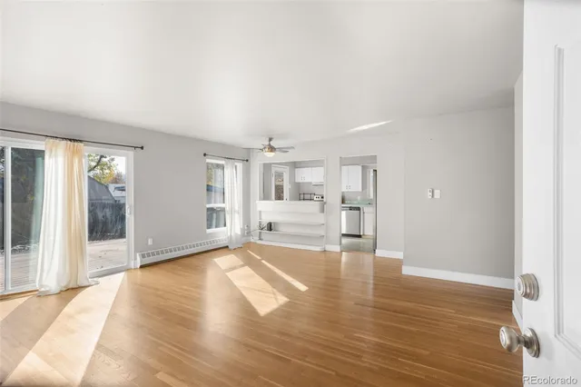 a view of an empty room with wooden floor and a window