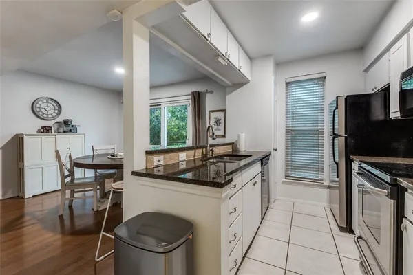 a kitchen with granite countertop a stove a sink and a refrigerator