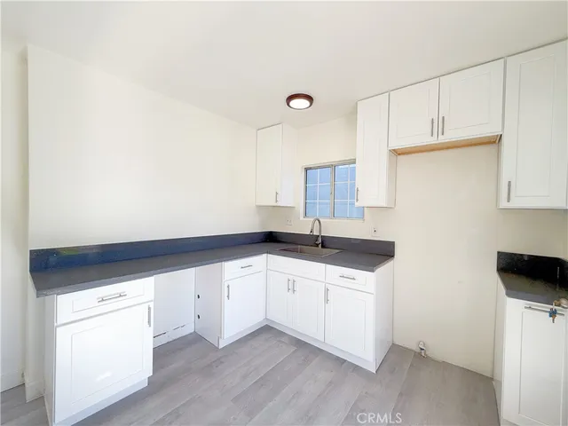 a kitchen with granite countertop white cabinets and a sink