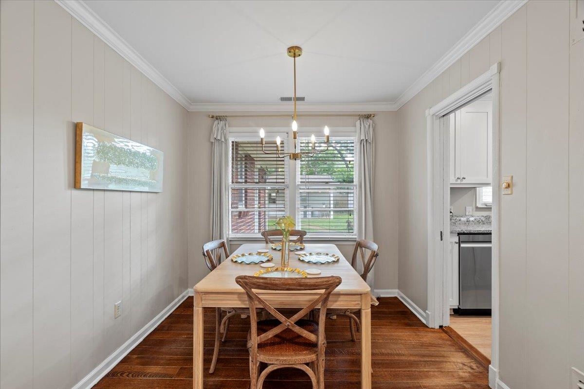 4491 Garnett Road Memphis, TN 38117 - Photo 8 of 32 Dining area featuring wood-finish flooring, vertical paneling, crown molding, and a brass-tone chandelier