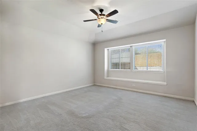 an empty room with a window and a ceiling fan