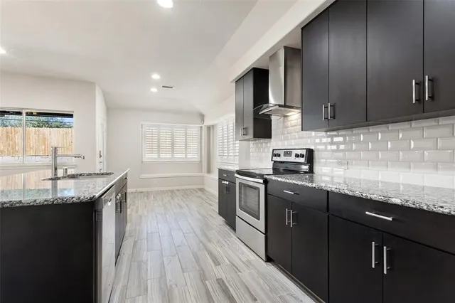 a kitchen with granite countertop wood cabinets stainless steel appliances and a window