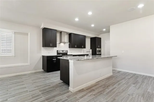 a kitchen with stainless steel appliances kitchen island granite countertop a stove a sink and a refrigerator