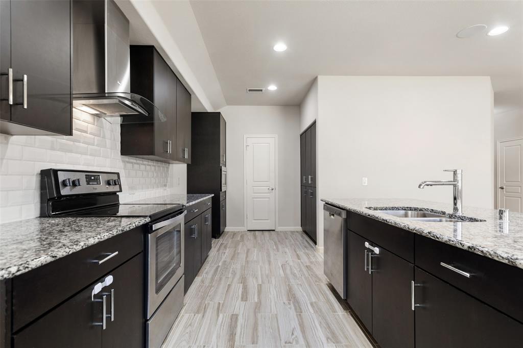 816 Harrison Lane Lavon, TX 75166 - Photo 10 of 40 a kitchen with stainless steel appliances granite countertop a sink a stove top oven a counter space and cabinets