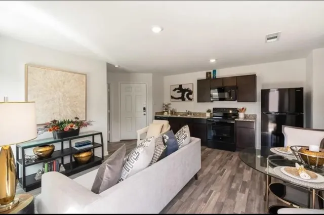 a living room with furniture kitchen and a wooden floor
