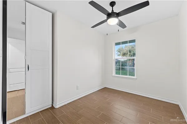 an empty room with ceiling fan and window