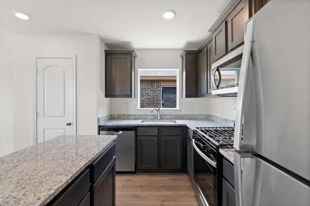 a kitchen with stainless steel appliances granite countertop a sink stove and cabinets