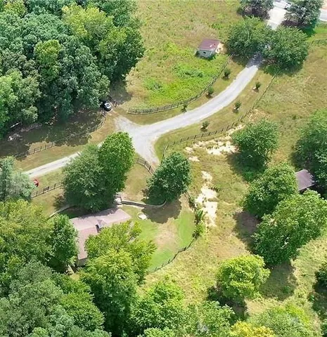 an aerial view of residential house with pool and trees all around