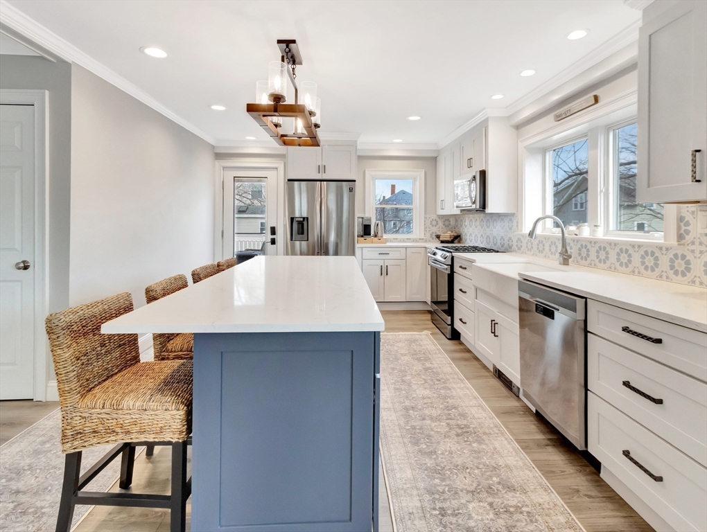 47 B Street, Unit BEACHSIDE Hull, MA 02045 - Photo 3 of 42 a large kitchen with stainless steel appliances kitchen island a table chairs in it and a window