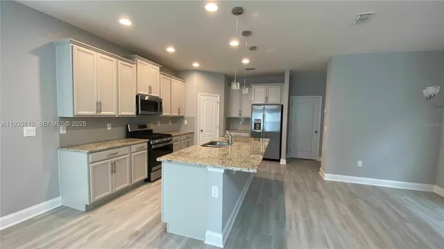 a kitchen with kitchen island granite countertop a sink cabinets and stainless steel appliances