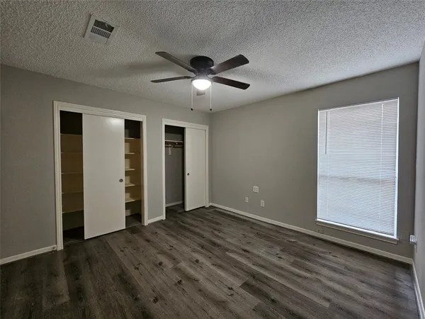 an empty room with wooden floor closet and ceiling fan