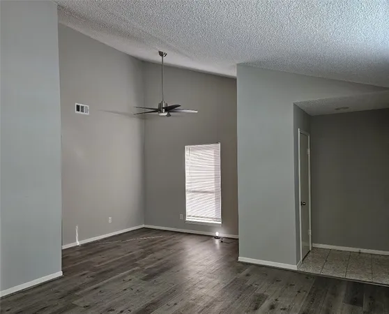 an empty room with wooden floor cabinet and windows