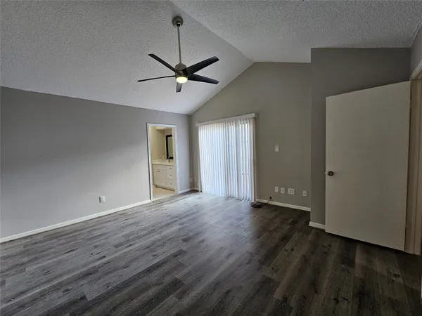 a view of an empty room with wooden floor and a ceiling fan