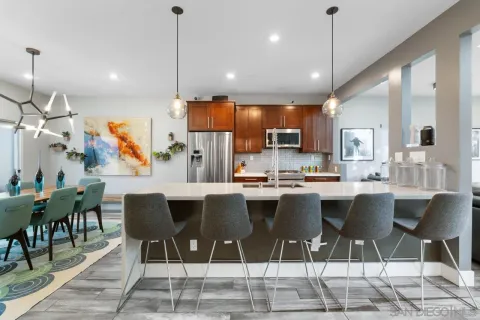 a kitchen with stainless steel appliances granite countertop a refrigerator a oven a sink dishwasher and couches with wooden floor