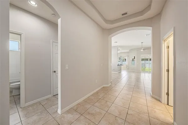 a view of an empty room with kitchen and window