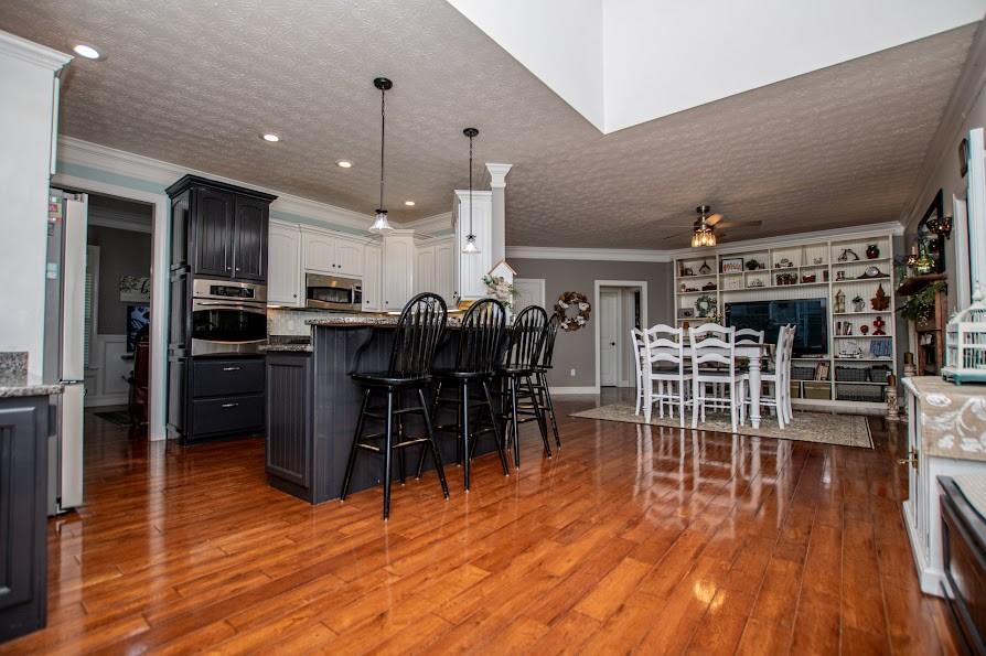 575 Liberty Church Road Carrollton, GA 30116 - Photo 21 of 95 a open kitchen with stainless steel appliances granite countertop a refrigerator a stove top oven a dining table and chairs with wooden floor