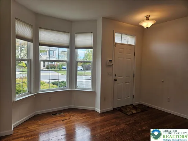a view of an empty room with window and wooden floor