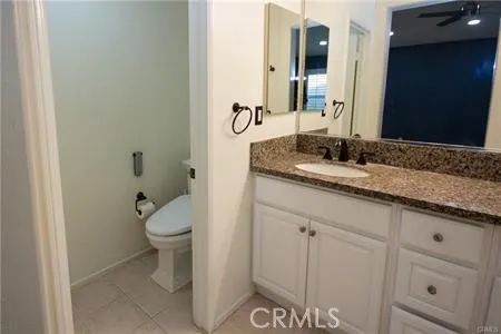 a bathroom with a granite countertop sink and a toilet