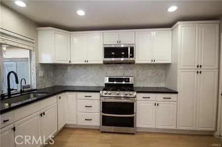 a kitchen with white cabinets and appliances