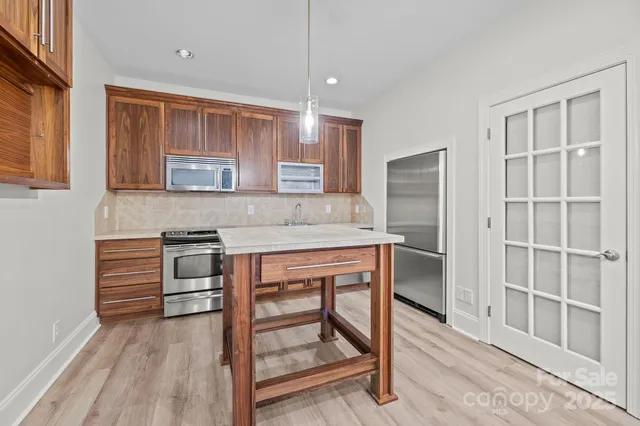 a kitchen with stainless steel appliances granite countertop a stove a sink and a refrigerator with wooden cabinets