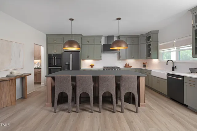 a large kitchen with stainless steel appliances granite countertop a stove a sink dishwasher a dining table and chairs with wooden floor