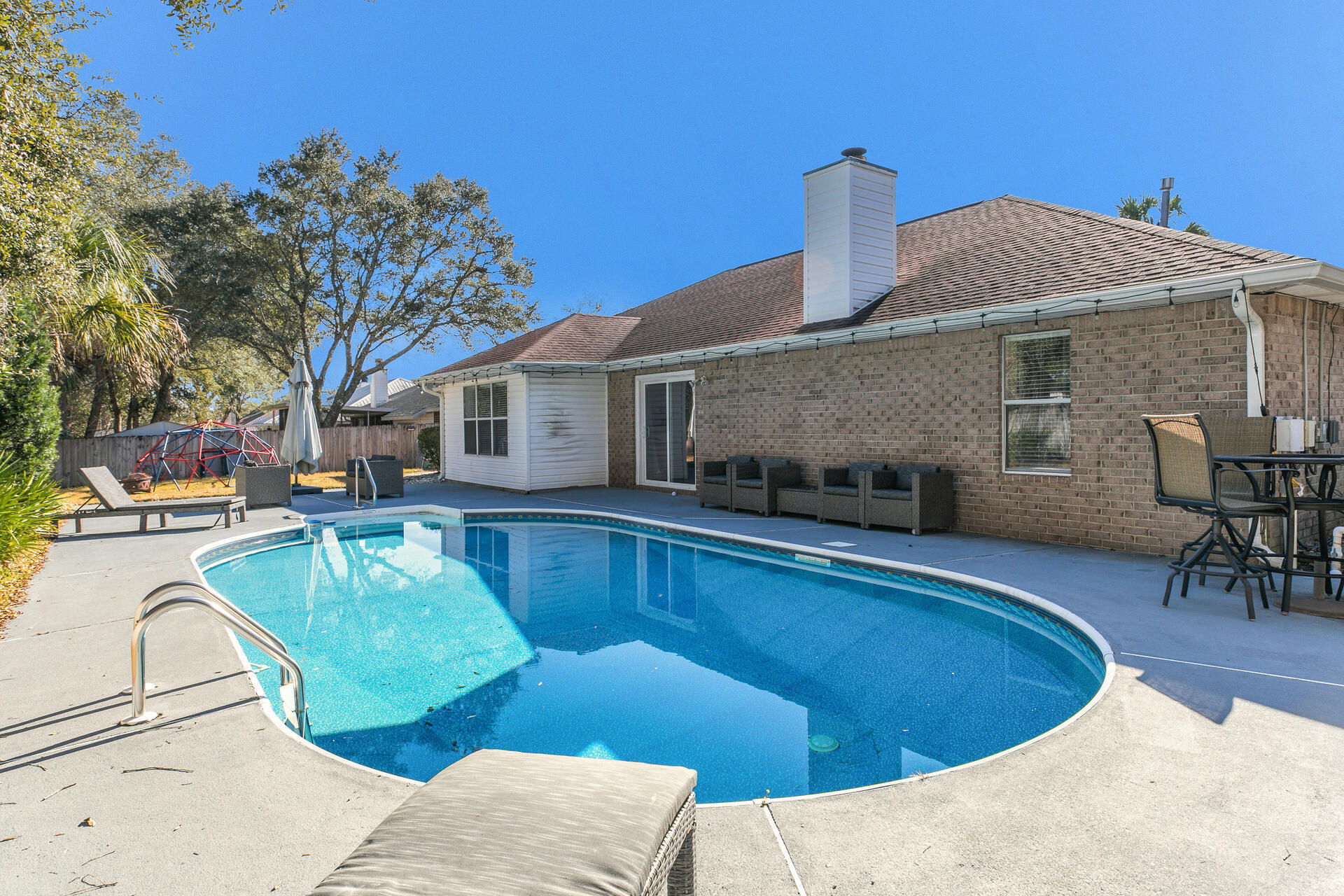 606 Risen Star Drive Crestview, FL 32539 - Photo 1 of 37 a view of a house with pool lawn chairs and a barbeque