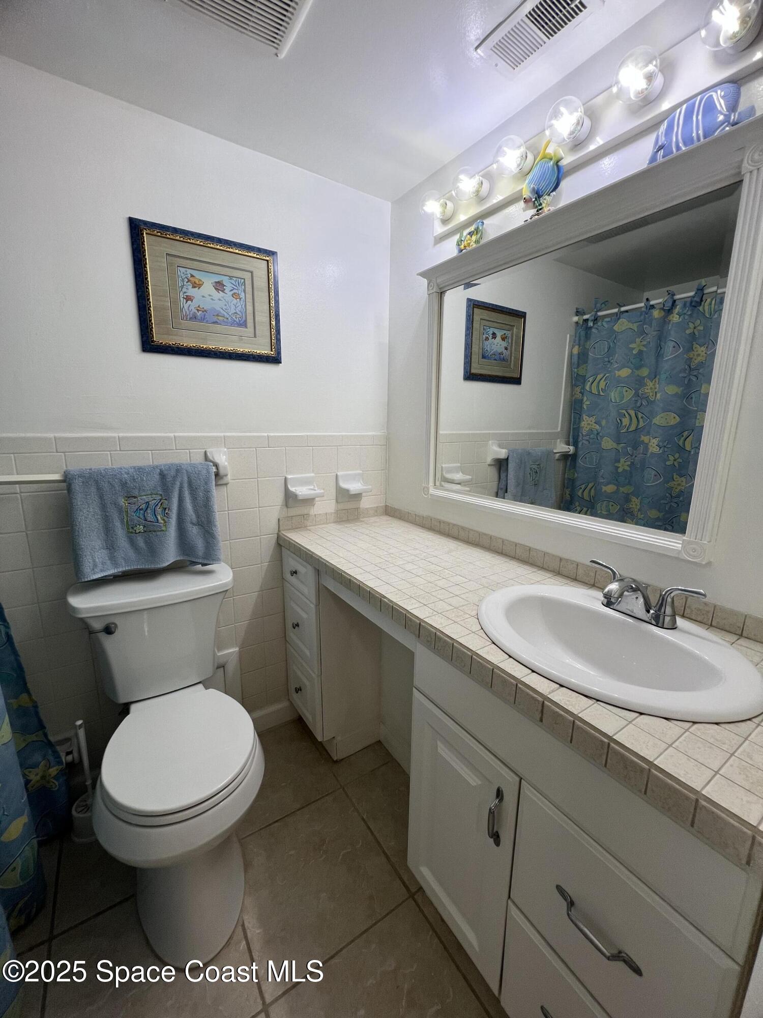 190 East Olmstead Drive, Unit E5 Titusville, FL 32780 - Photo 12 of 26 a bathroom with a toilet a sink and mirror