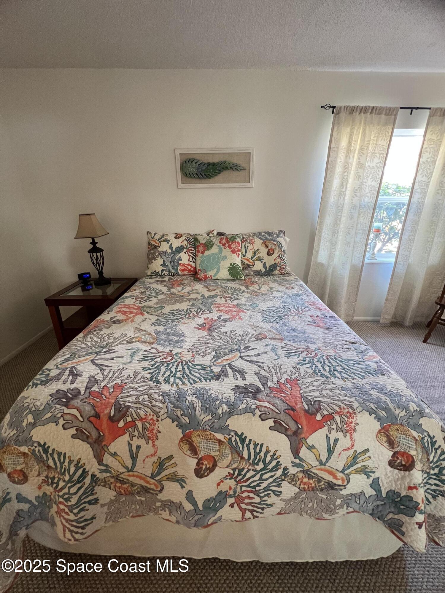 190 East Olmstead Drive, Unit E5 Titusville, FL 32780 - Photo 16 of 26 a bed sitting in a bedroom next to a window