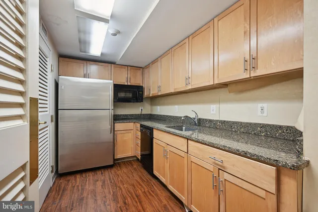 a kitchen with granite countertop stainless steel appliances a refrigerator a sink and cabinets