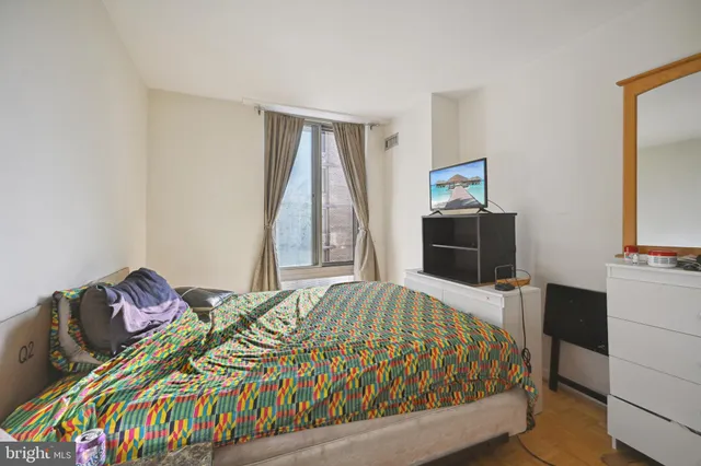 a bedroom with a bed and a flat tv screen on a dresser