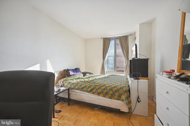 a bedroom with a bed and a flat tv screen on the dresser