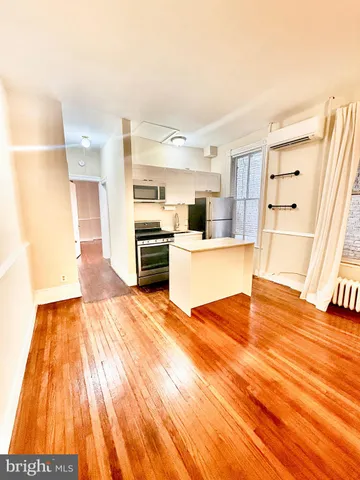 a large white kitchen with granite countertop a stove top oven a sink and dishwasher with wooden floor