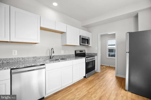 a kitchen with granite countertop a sink stove and refrigerator