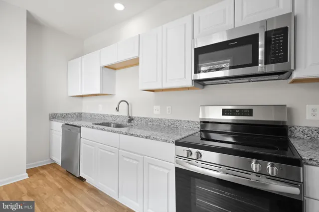 a kitchen with stainless steel appliances granite countertop a sink and a stove