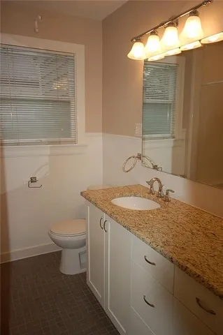 a bathroom with a granite countertop sink and a toilet